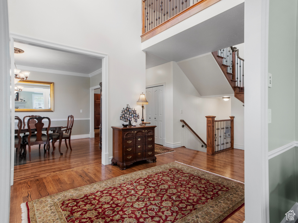 Foyer with wood finished floors, a notable chandelier, crown molding, stairway, and baseboards