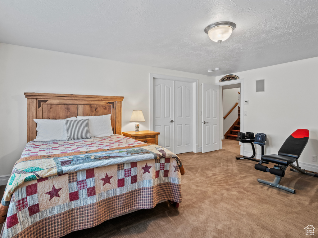 Bedroom with a textured ceiling, carpet, a closet, and baseboards