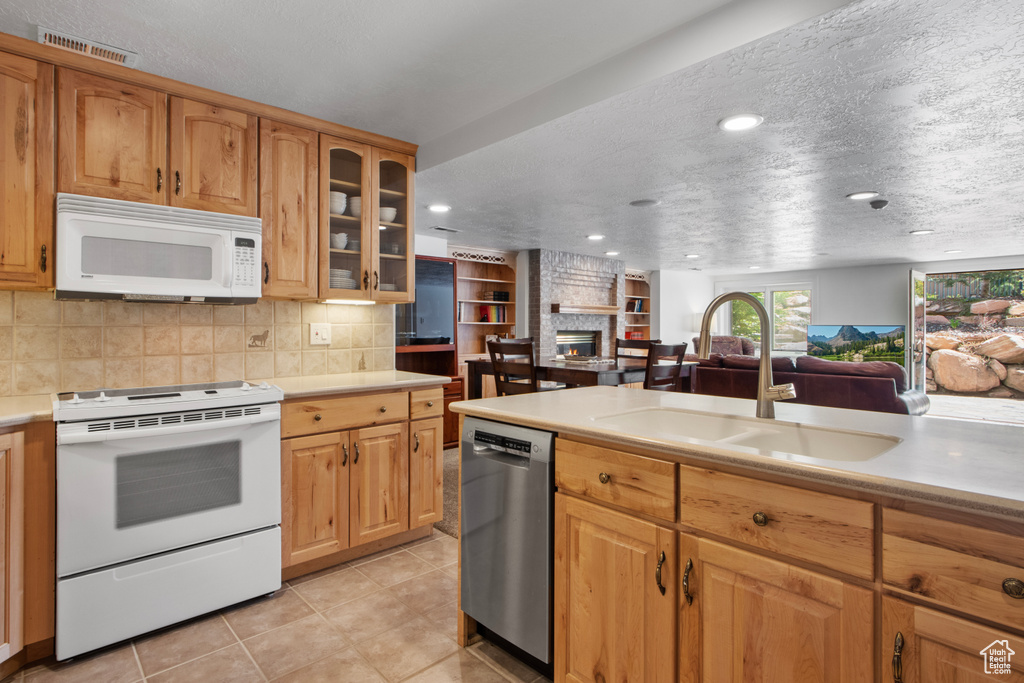 Kitchen featuring a sink, a fireplace, open floor plan, visible vents, and white appliances