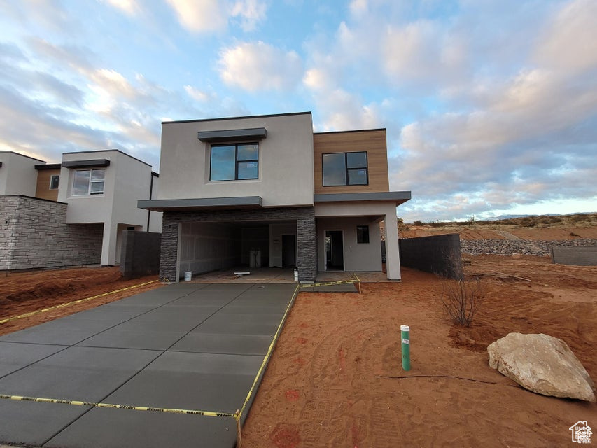 Contemporary house featuring stucco siding, concrete driveway, a garage, and stone siding