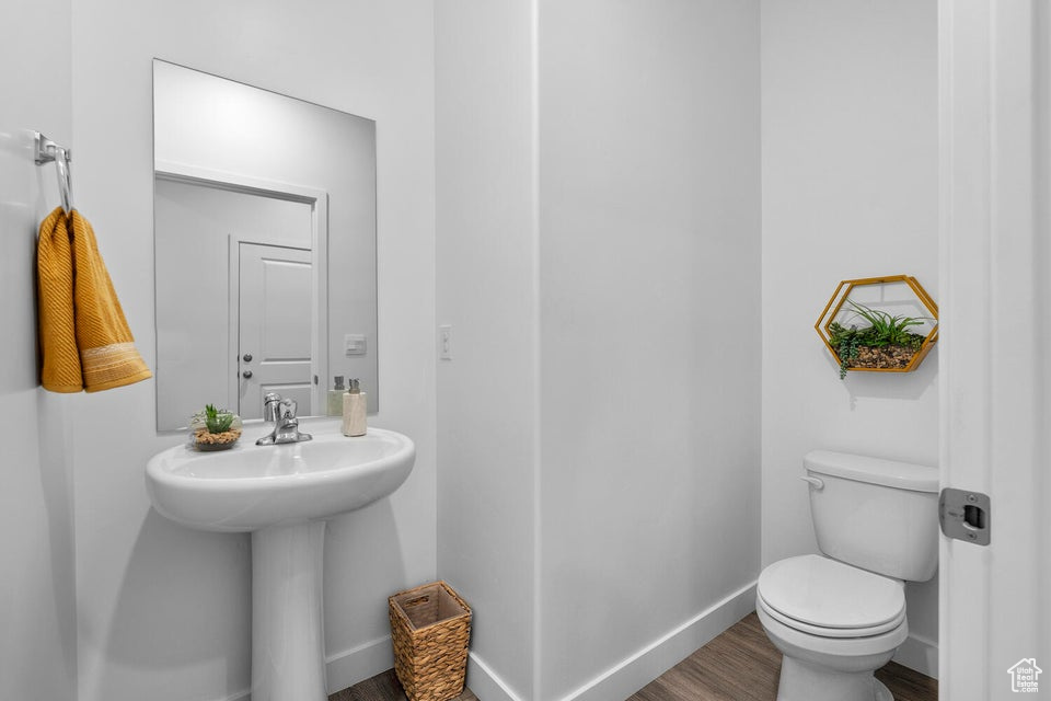 Bathroom featuring wood finished floors, baseboards, toilet, and a sink