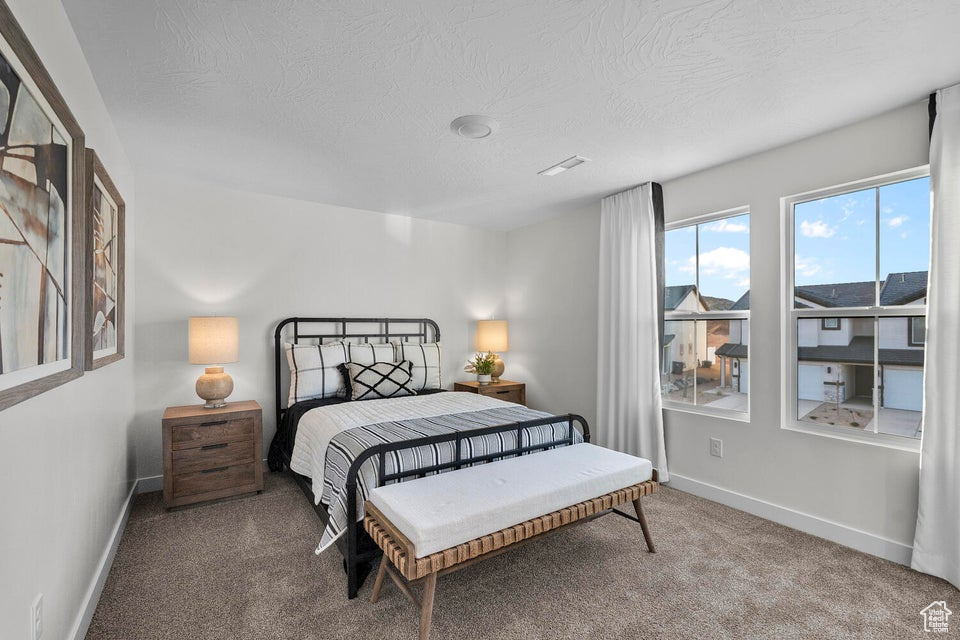 Carpeted bedroom featuring baseboards and a textured ceiling