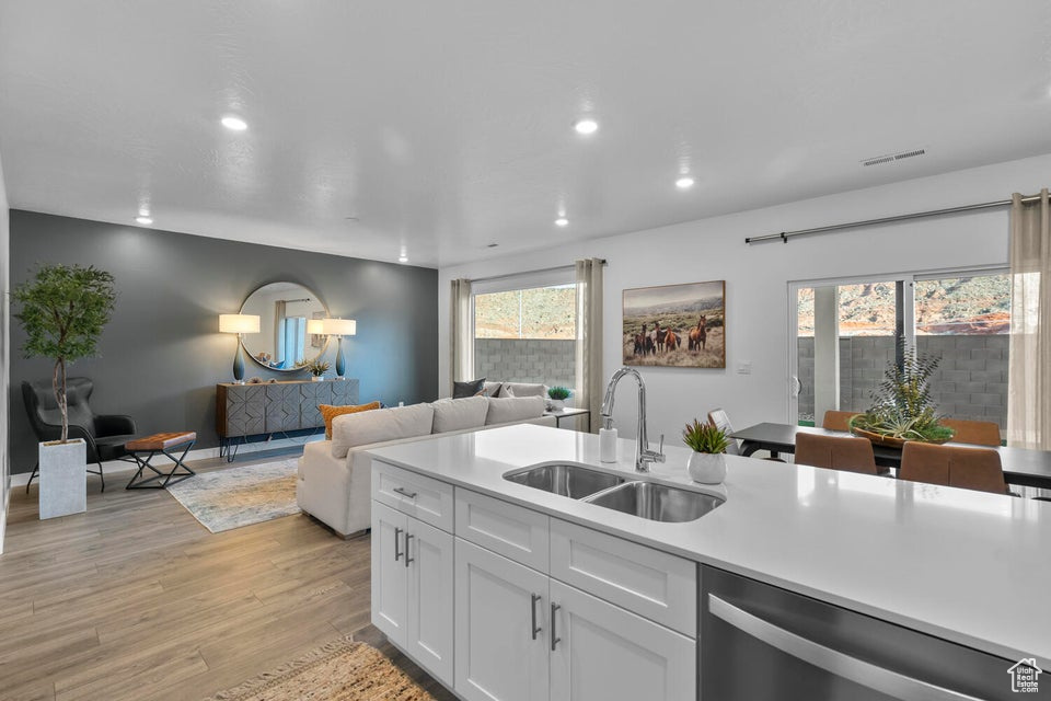 Kitchen with a sink, stainless steel dishwasher, recessed lighting, light wood-type flooring, and light countertops