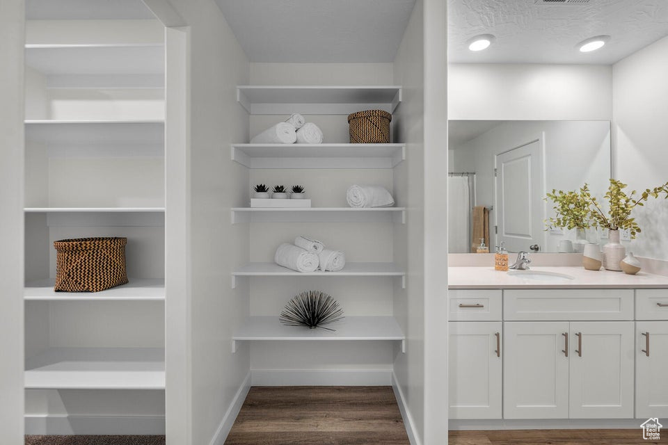 Full bathroom with vanity, wood finished floors, and baseboards