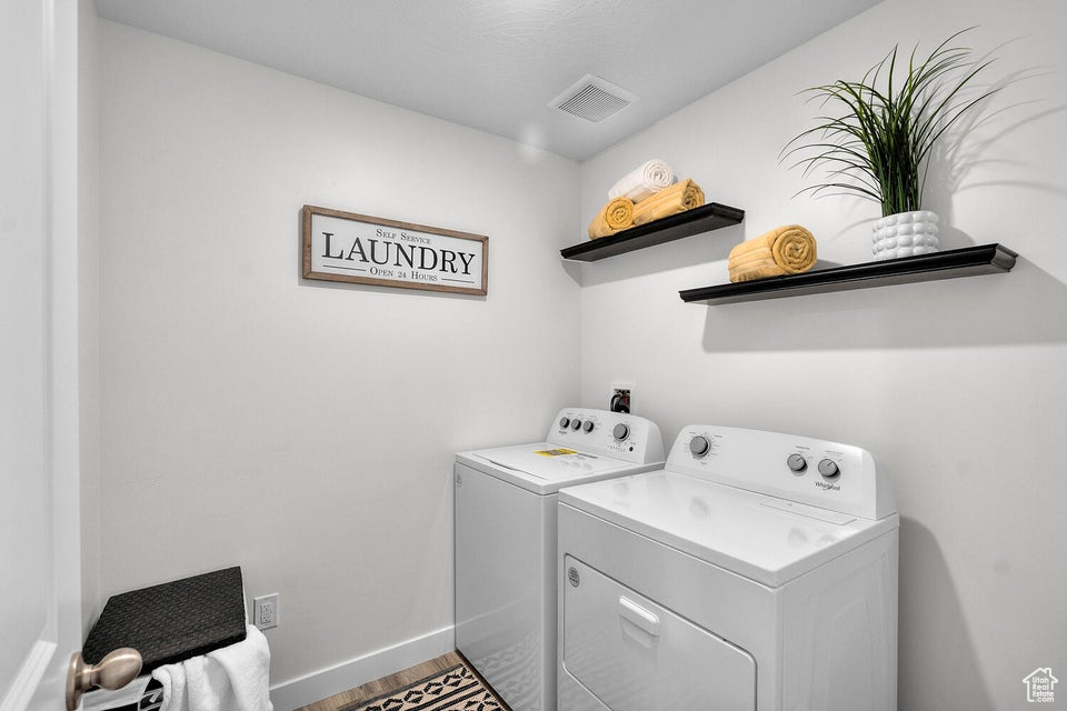 Laundry room featuring washer and dryer, wood finished floors, and baseboards