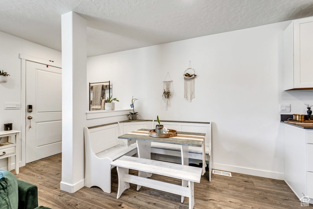 Dining area with light wood finished floors, a textured ceiling, and baseboards