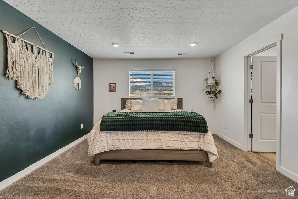 Bedroom featuring carpet floors, baseboards, and a textured ceiling