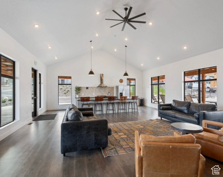 Living room with dark wood-type flooring, ceiling fan, high vaulted ceiling, and recessed lighting