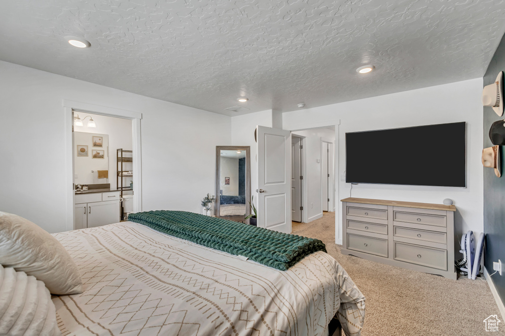 Carpeted bedroom featuring a textured ceiling, ensuite bath, and recessed lighting