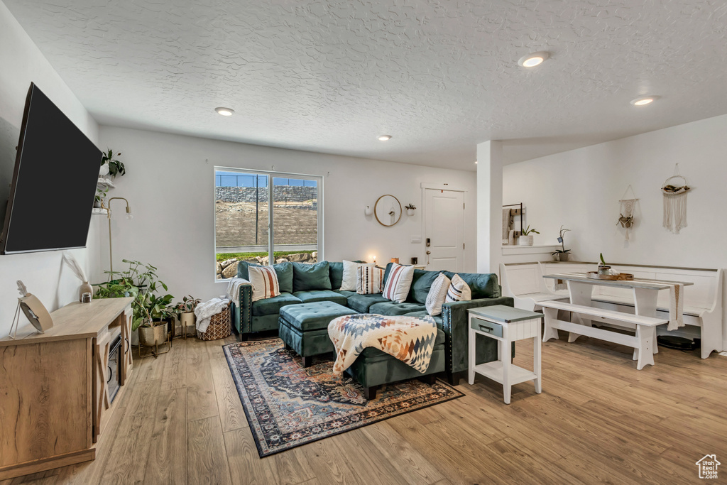 Living room featuring a textured ceiling, light wood-type flooring, and recessed lighting
