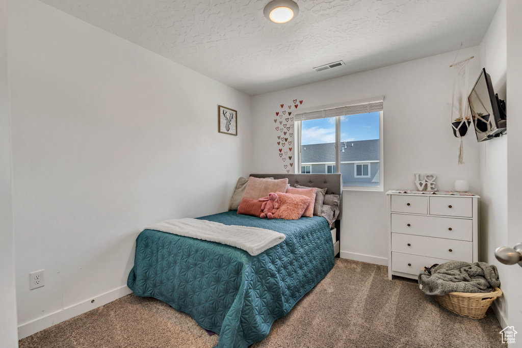 Bedroom with carpet floors, baseboards, and a textured ceiling