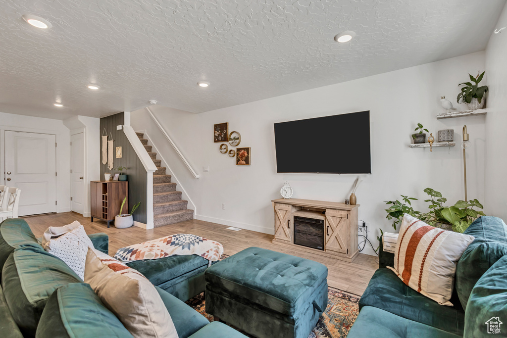 Living area with stairs, wood finished floors, a textured ceiling, recessed lighting, and baseboards
