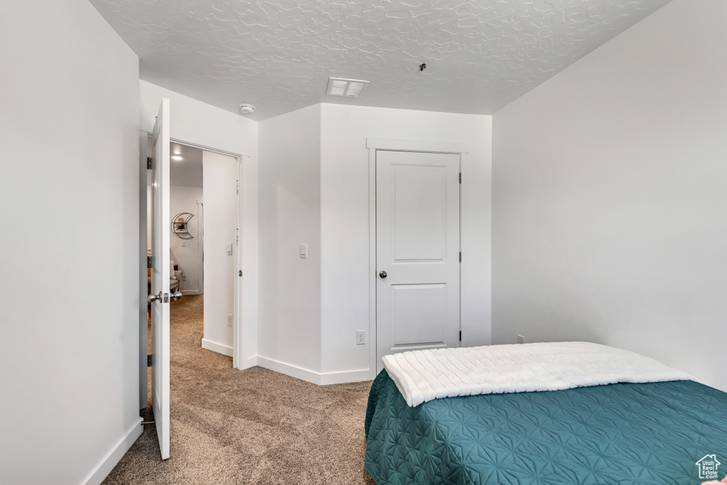 Bedroom with carpet floors, baseboards, and a textured ceiling