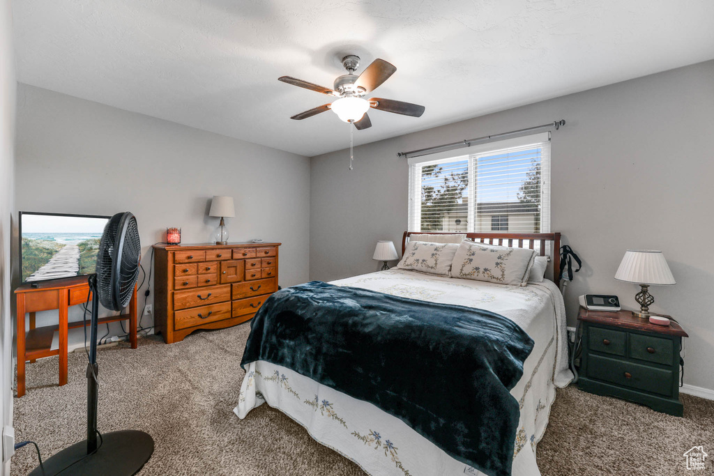 Carpeted bedroom with a ceiling fan