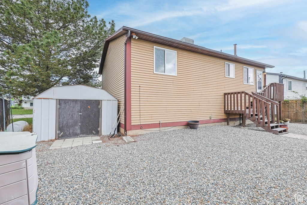 Rear view of property featuring a storage unit, fence, and an outbuilding