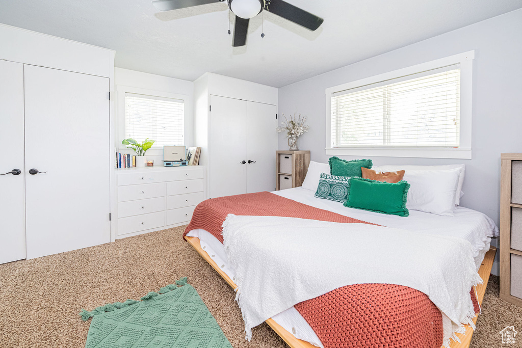Carpeted bedroom with multiple closets and ceiling fan