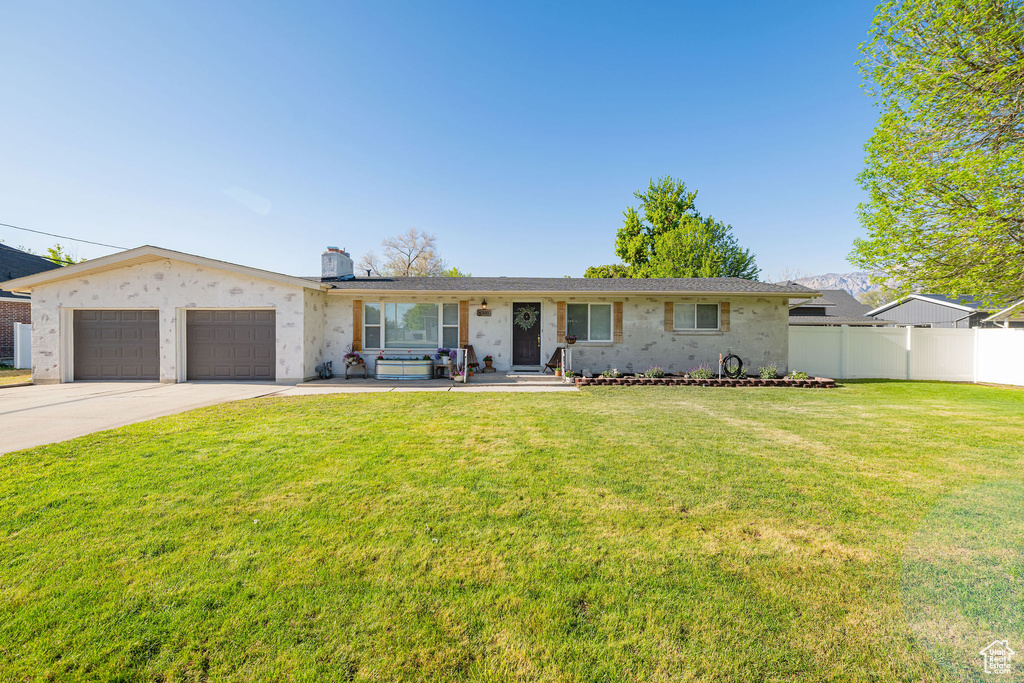Ranch-style house featuring an attached garage, concrete driveway, and a chimney