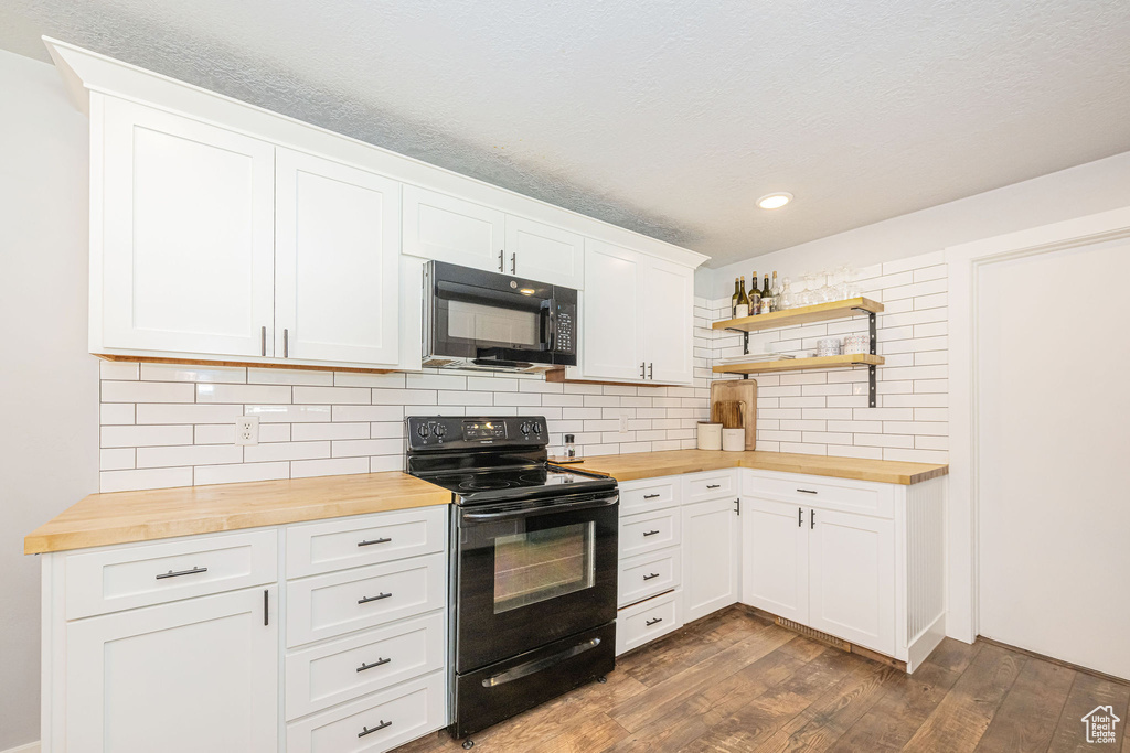 Kitchen with wooden counters, black appliances, dark wood finished floors, open shelves, and decorative backsplash