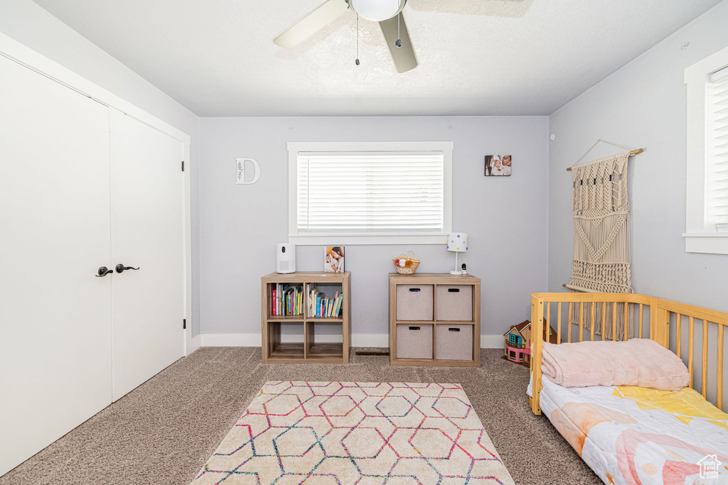 Bedroom with light carpet, a closet, and a ceiling fan