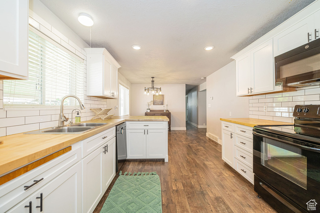 Kitchen featuring black appliances, butcher block countertops, a sink, white cabinets, and recessed lighting