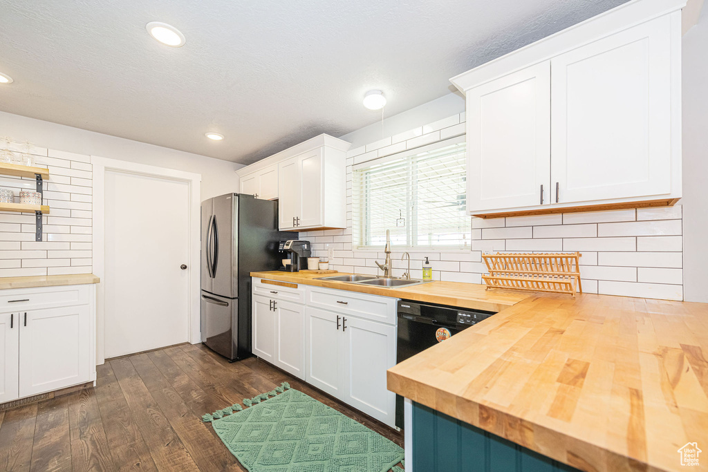 Kitchen featuring wooden counters, freestanding refrigerator, a sink, dark wood-style floors, and tasteful backsplash