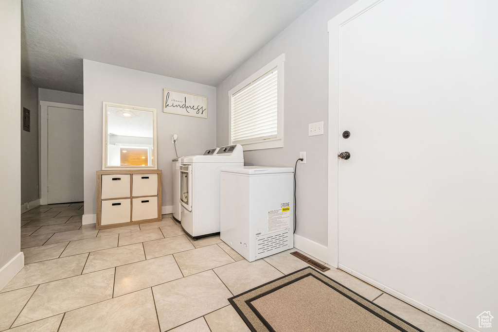 Laundry room with washing machine and dryer, light tile patterned floors, and baseboards