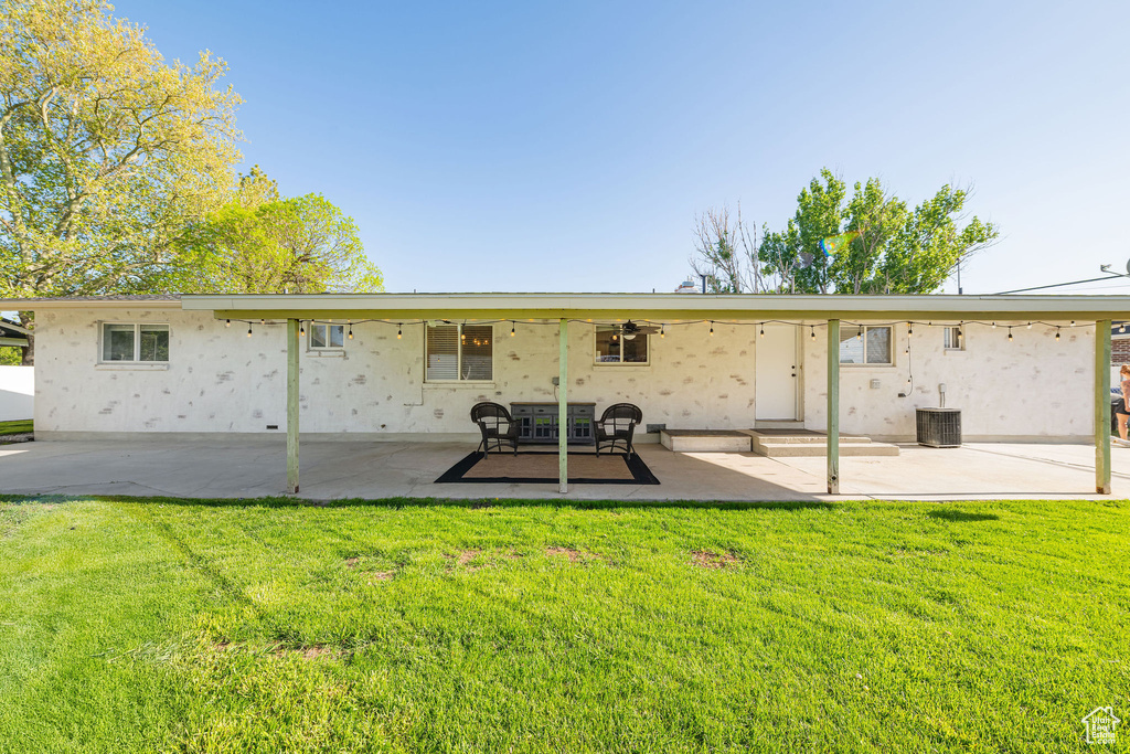 Back of property featuring a patio area, a lawn, a ceiling fan, and stucco siding