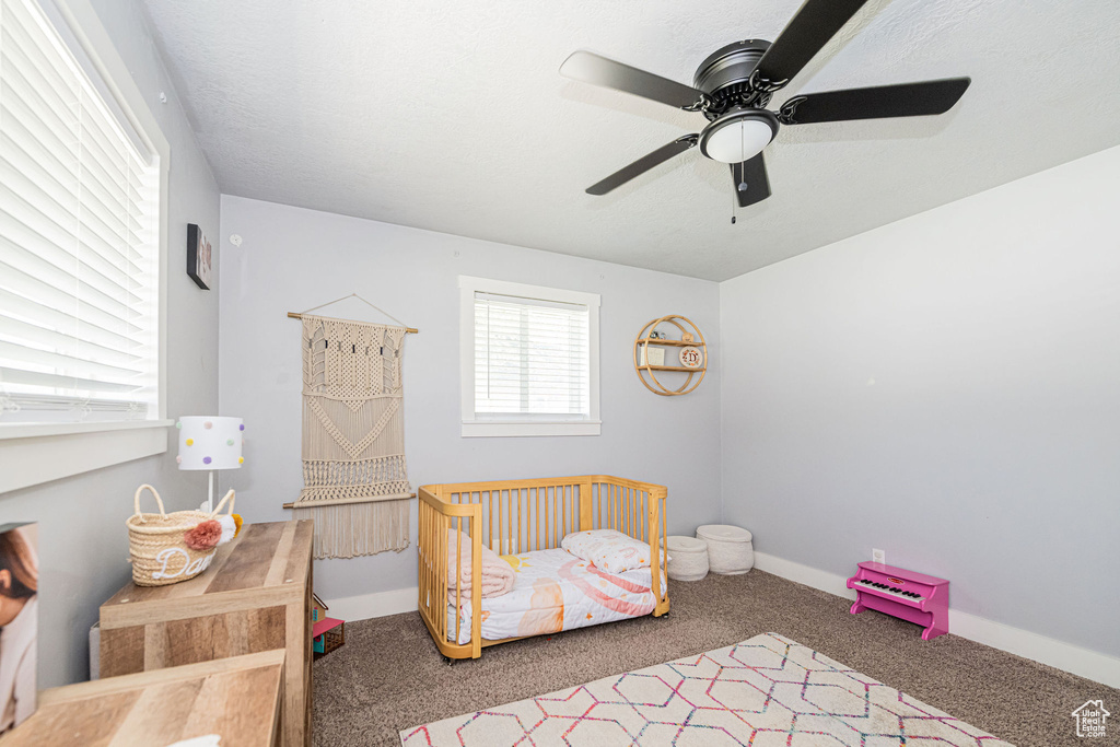 Carpeted bedroom featuring ceiling fan and baseboards