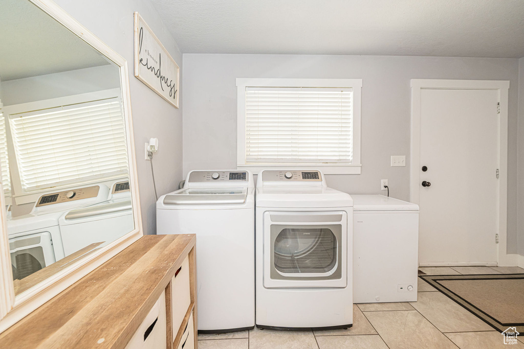 Clothes washing area with washer and dryer and light tile patterned flooring