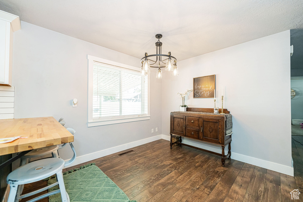 Dining area with a chandelier, dark wood-style floors, and baseboards