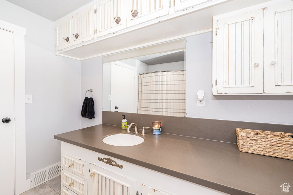 Bathroom with vanity, tile patterned floors, and baseboards