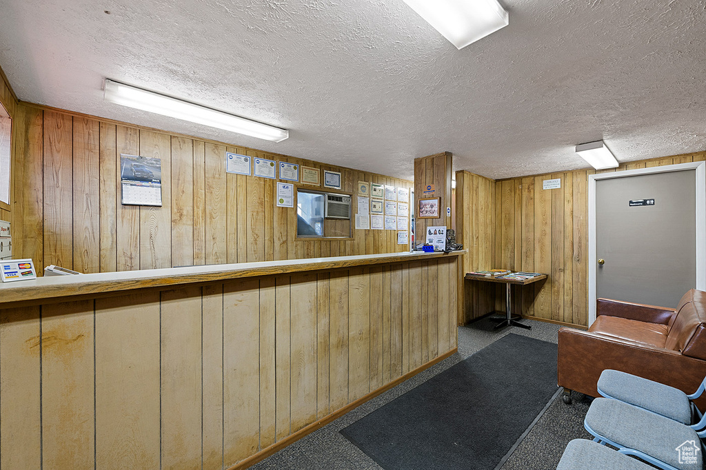 Bar area featuring wooden walls, a textured ceiling, and carpet flooring