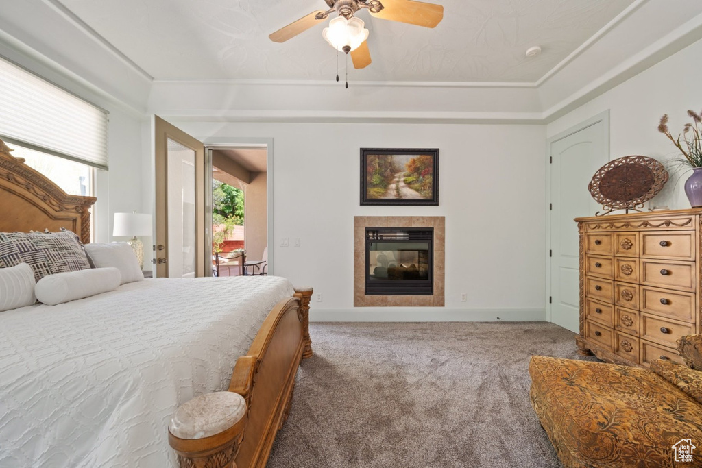 Carpeted bedroom with a tiled fireplace, ceiling fan, and baseboards