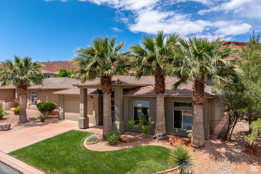 View of front of home featuring an attached garage, driveway, stucco siding, and a tiled roof