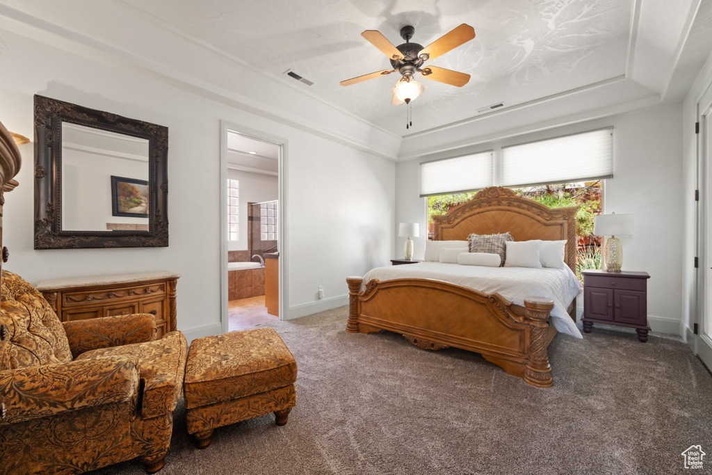 Bedroom featuring a raised ceiling, carpet flooring, ensuite bath, baseboards, and ceiling fan