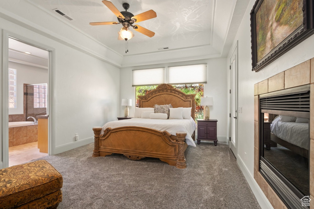 Bedroom featuring light carpet, a raised ceiling, ensuite bathroom, baseboards, and ceiling fan