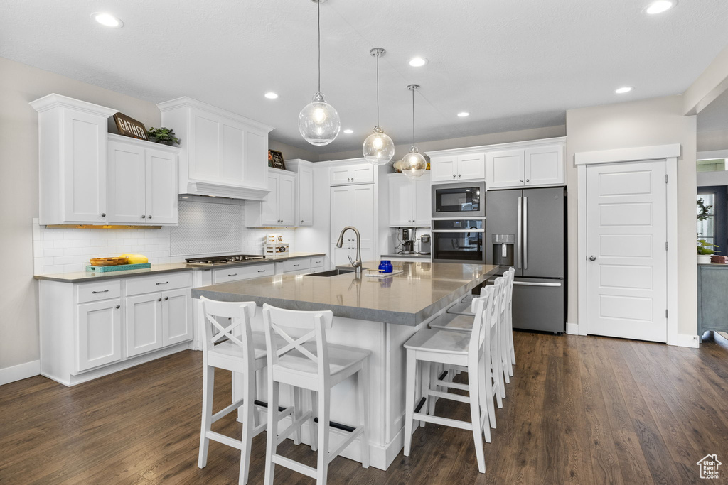 Kitchen with stainless steel appliances, white cabinetry, a sink, and recessed lighting
