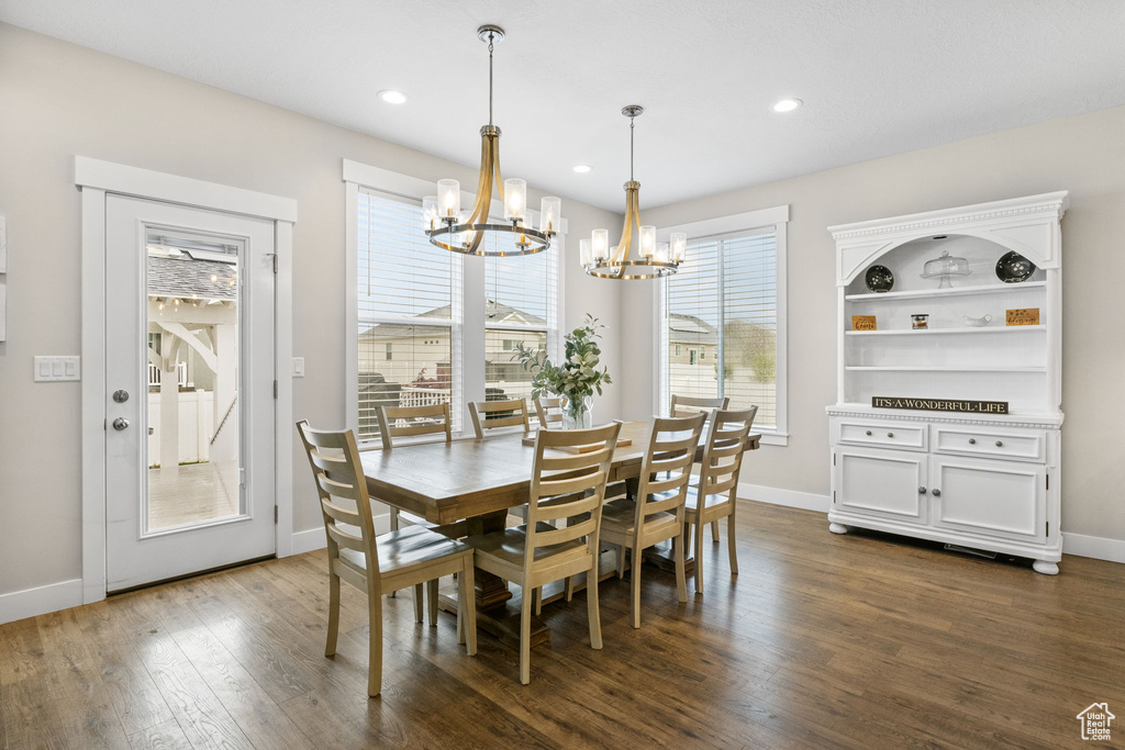 Dining space with a chandelier, dark wood finished floors, baseboards, and recessed lighting