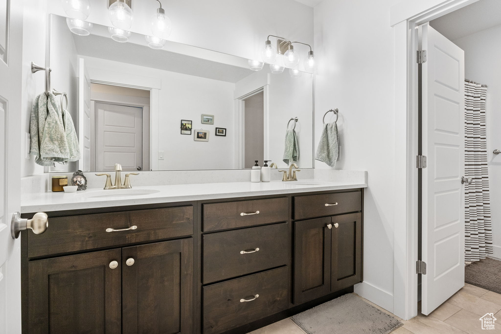 Full bathroom with double vanity, tile patterned floors, and baseboards