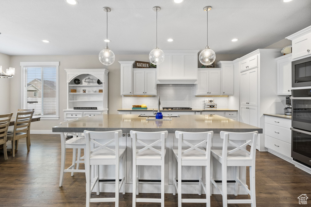 Kitchen with built in microwave, a sink, tasteful backsplash, dark wood-type flooring, and recessed lighting