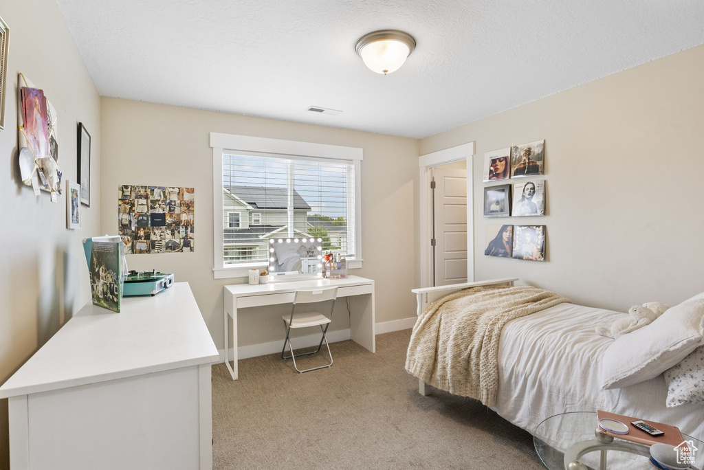 Bedroom featuring light colored carpet, baseboards, and a desk