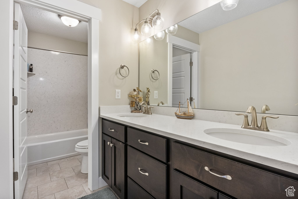 Bathroom featuring double vanity, toilet, and shower / tub combination