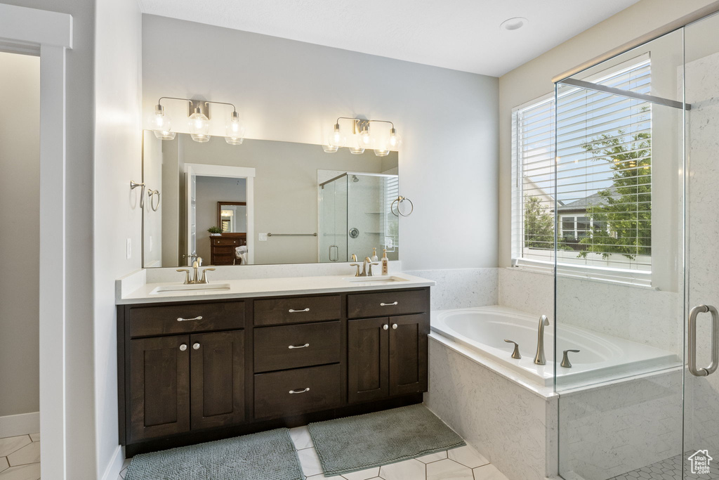 Ensuite bathroom featuring tile patterned floors, a shower stall, a bath, and double vanity