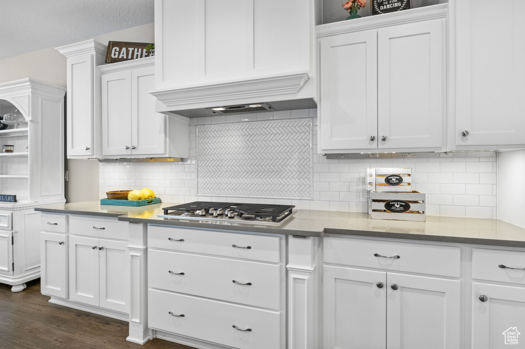 Kitchen featuring stainless steel gas stovetop, white cabinetry, open shelves, dark wood-type flooring, and decorative backsplash