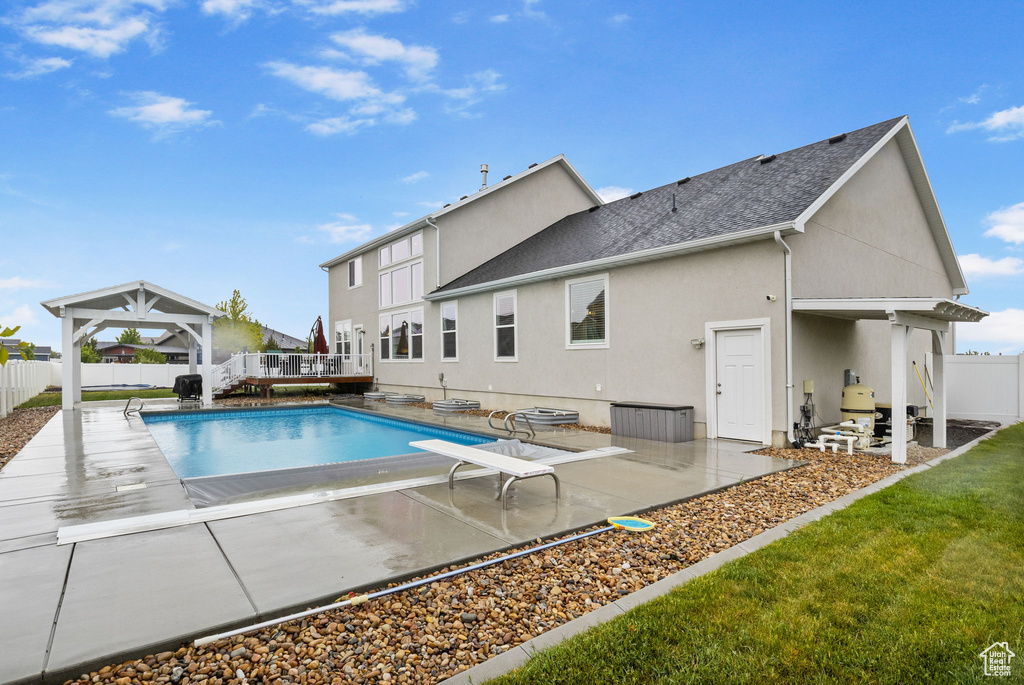 View of pool featuring a fenced backyard, a gazebo, a wooden deck, a patio, and a diving board