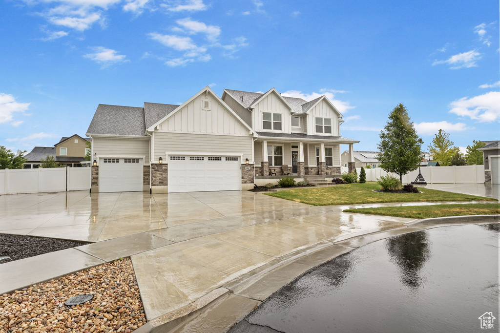 Craftsman-style house featuring board and batten siding, a porch, driveway, a garage, and stone siding