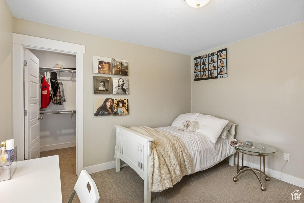 Carpeted bedroom with a closet, baseboards, and a walk in closet