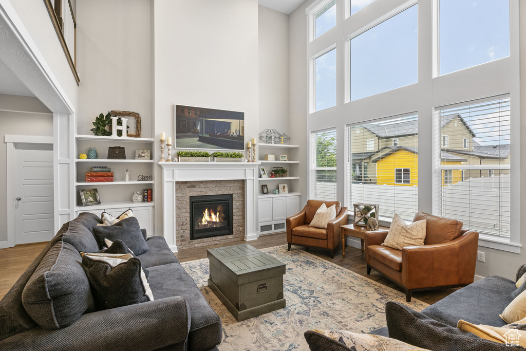 Living room with wood finished floors, a high ceiling, plenty of natural light, and a fireplace