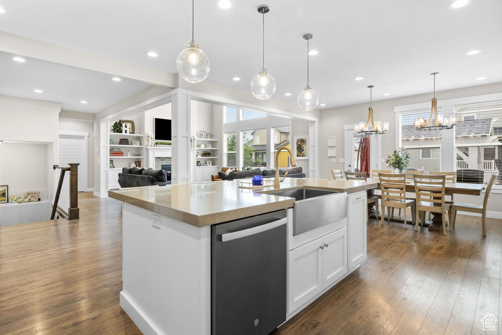 Kitchen with dishwasher, a sink, dark wood-type flooring, an island with sink, and plenty of natural light