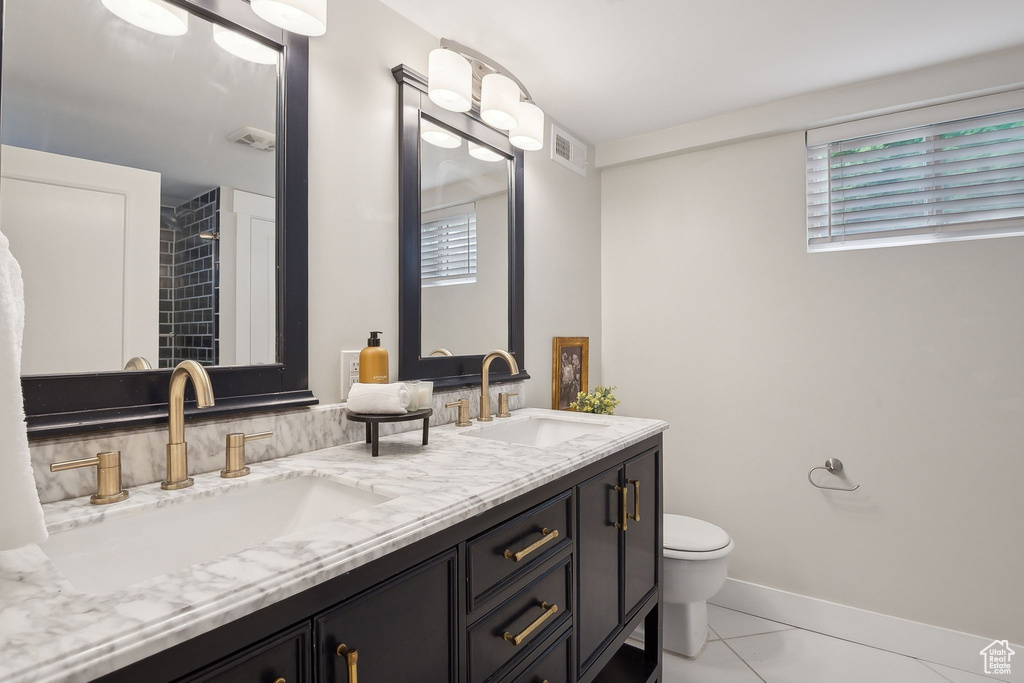 Full bath featuring toilet, double vanity, and baseboards